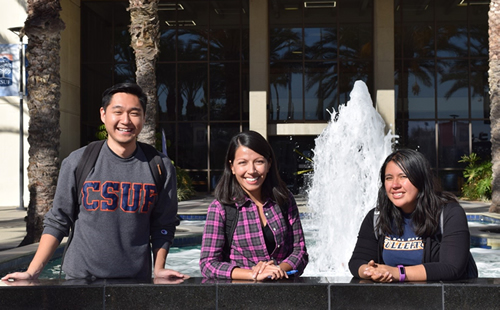 graduate students standing infront of csuf sign